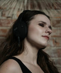 Person enjoying music wearing headphones in front of a brick wall background.