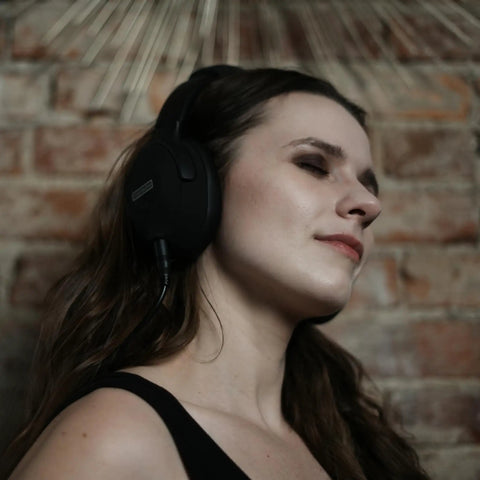 Person enjoying music wearing headphones in front of a brick wall background.