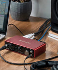 Scarlett 4i4 3rd Gen USB Audio Interface for Recording Songwriting and Streaming on a desk with laptop and studio monitor