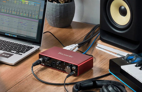 Scarlett 4i4 3rd Gen USB Audio Interface for Recording Songwriting and Streaming on a desk with laptop and studio monitor