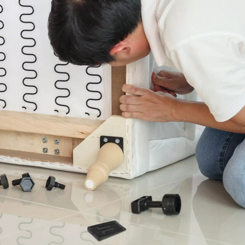 Man installing 20 Pack Black Adjustable Furniture Leveling Pads Anti Slip Shims under a sofa to reduce vibration