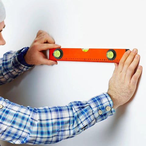 Person using 4pcs Acrylic Cylindrical Mini Spirit Level Tool for Precise Measuring against a wall for accurate leveling.