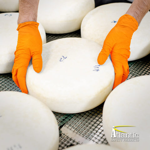 Outrageous Orange Heavy Duty Disposable Nitrile Gloves handling cheese wheels in food prep area.