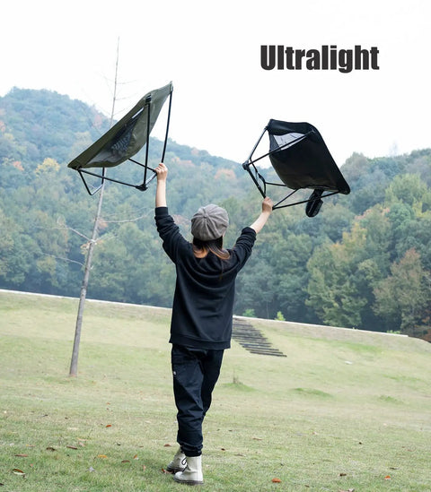 Person holding Ultralight Low Profile Camping Folding Chair with Side Pocket and Carry Bag 7.5 Inch Seat Height in a park