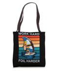 Black tote with "Work Hard Foil Harder" text and wing foil surfer graphic, 16x16 inches, durable material.