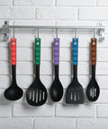Five colorful kitchen spatulas hanging on a rack, featuring solid black heads and vibrant handles in red, green, purple, blue, and brown.