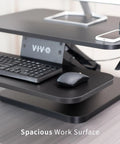 Close-up of No Brainer Height Adjustable 25 Inch Standing Desk Converter with keyboard and mouse on black tabletop.