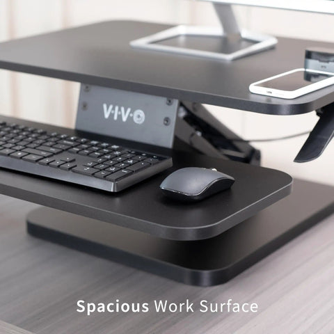 Close-up of No Brainer Height Adjustable 25 Inch Standing Desk Converter with keyboard and mouse on black tabletop.