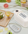 Great Slick And Totally Nifty Mini Countertop Ice Maker With 12V Car Adapter And Fast Freeze Cycle, white unit beside drinks and food.
