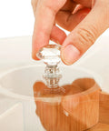 Person placing a crystal knob on a Top Grade Bamboo Serving Platter With Built-In Dividers, 12 Inch Snack Board For Fresh Fruit And Nuts.