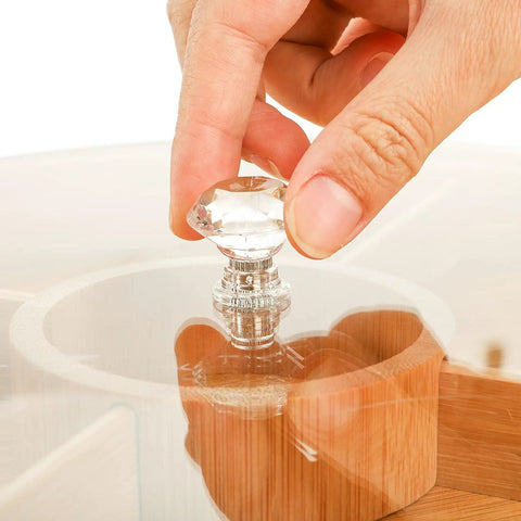 Person placing a crystal knob on a Top Grade Bamboo Serving Platter With Built-In Dividers, 12 Inch Snack Board For Fresh Fruit And Nuts.