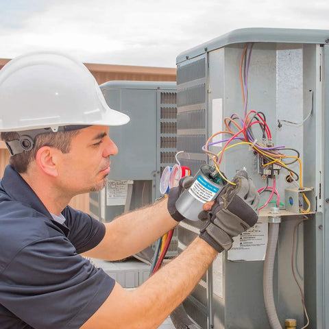 Technician installing 45 Plus 5 uF Dual Run Round AC Capacitor For Air Conditioning Units 370/440 VAC CBB65B in HVAC system