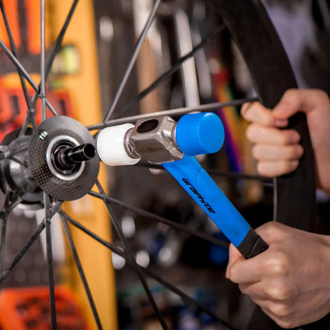 Double Face Rubber Mallet 12 Oz With White Nylon Head And Blue Soft Face, used on bike wheel, graphite core handle visible