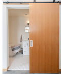 Dead Simple Seven Inch Recessed Pocket Door Pull With Rock Solid Rust Proof Brushed Stainless Steel Slide Grip Handle For Easy Glide Barn Doors And Tight Cabinet Installations on a sliding barn door opening to a bathroom.