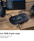 Vocaster Two Podcasting Interface with mic, headphones, computer, Auto Gain, Enhance shown on wooden table