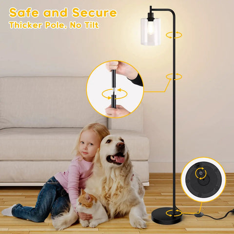 Lit Industrial Floor Lamp In Black And Gold With Clear Glass Shade shown next to a child and dog in a living room setting