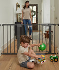 Auto Close Baby Gate For Stairs And Doorways With Easy Install Pressure Mounted Design Walk Through One Hand Operation Perfect For Pets And Little Ones In Black in hallway with child playing