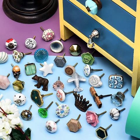 Diverse collection of decorative cabinet knobs displayed around a small chest, showcasing variety in style and design.
