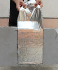 Person demonstrating Heavy Duty Roof Underlayment Roll with aluminum cladding and waterproof membrane on gray concrete.