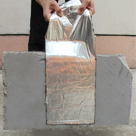 Person demonstrating Heavy Duty Roof Underlayment Roll with aluminum cladding and waterproof membrane on gray concrete.