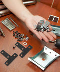 Hand holding Black Stainless Steel T Shape Flat Angle Brackets with Countersunk Screw Holes for chairs and tables DIY projects