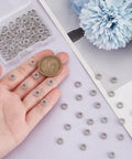 Silver Flower Spacer Beads 100 Pcs Daisy Rondelle Beads For DIY Jewelry Making shown with coin for scale.