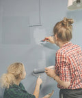 Two women painting a wall with a Heavy Duty 6 By 8 Inch Drywall Access Panel With Secure Hinged Cover visible.