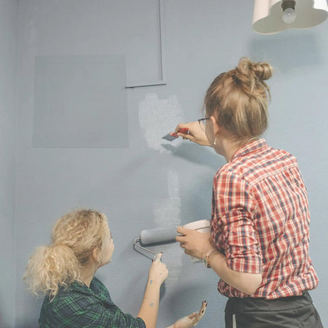 Two women painting a wall with a Heavy Duty 6 By 8 Inch Drywall Access Panel With Secure Hinged Cover visible.