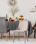 Dining scene featuring grey and beige chairs around a table with food, drinks, and a mirror reflecting decor.