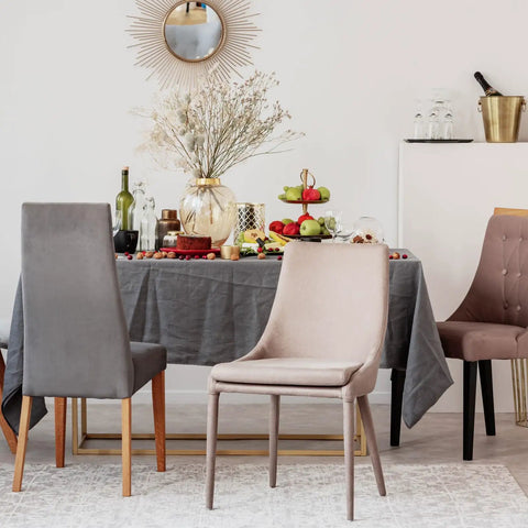 Dining scene featuring grey and beige chairs around a table with food, drinks, and a mirror reflecting decor.