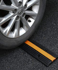 Heavy Duty Rubber Cable Ramp 2 Channel Drive Over Protector under car wheel on asphalt, showing durability and use.