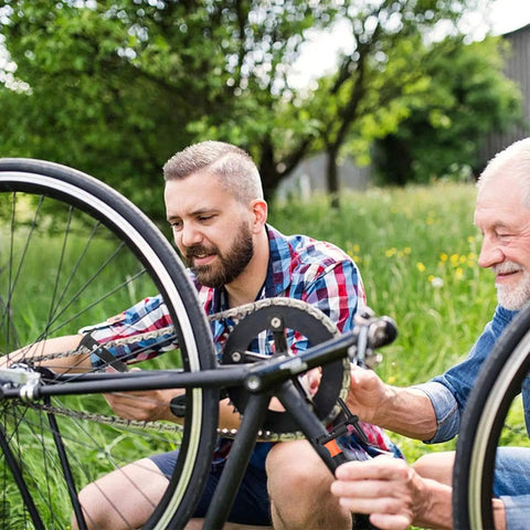 Two men repairing a bike using the Pro Grade Bike Chain Repair Tools Kit With Chain Breaker Master Link Pliers Wear Indicator.