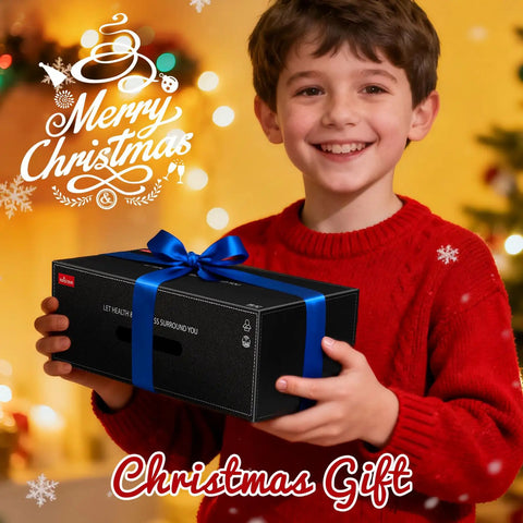 Smiling child in red sweater holding a black gift box with blue ribbon, Christmas decorations in background