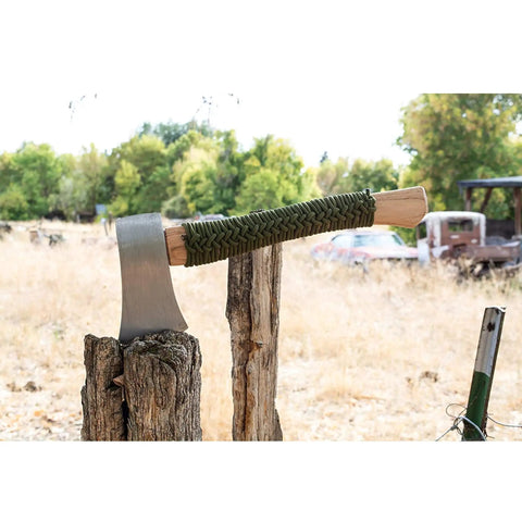 Hatchet with Hardcore 550 Paracord Rope Nylon Parachute Cord grip in outdoor survival setting.