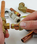 Close-up of hands installing brass compression fitting with sleeve ferrule on 9mm copper tube