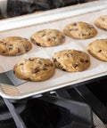 Mini stainless steel spatula set (2 pieces) on a cookie sheet with chocolate chip cookies