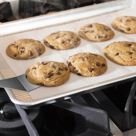 Mini stainless steel spatula set (2 pieces) on a cookie sheet with chocolate chip cookies