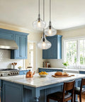 WILON 11" Hammered Glass Pendant Lights Kitchen Island Black hanging above a modern blue kitchen island with marble countertop.