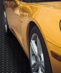 Yellow car parked on Heavy Duty Diamond Plate Rubber Flooring Roll 12 Inch By 20 Foot Non Slip Garage Mat For Workshop Outdoor Use.
