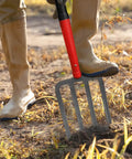 Heavy Duty 4-Tine Garden Spading Fork With 43 Inch Fiberglass Handle being used for soil digging