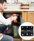 Black iron cabinet hinge being installed in a wooden kitchen cabinet with a drill.