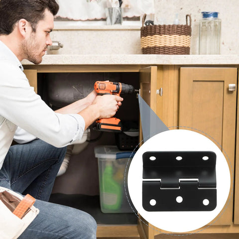 Black iron cabinet hinge being installed in a wooden kitchen cabinet with a drill.