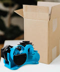 Semi Automatic Heat Tape Cutter With Compact Desktop Packing Station And Lightweight Tape Holder For Quick Box Sealing And Top Shelf Shipping Hustle The Reliable Gadget For Smooth Tape Dispensing Routine Blue next to an open cardboard box.