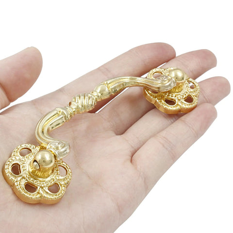 Person holding gold drop bail drawer pull, part of 4 pack 120mm cabinet handles, modern dresser hardware. Durable zinc alloy, rust resistant.