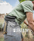 Compact Pack Hatchet With 3.5 Inch Steel Blade, Full Tang, Ergonomic Rubber Grip in sheath on person's belt during outdoor use.