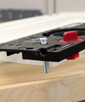 Close-up of concealed cabinet hinge jig with 35mm Forstner bit and metal bushing drill guide for precise hinge cup holes.