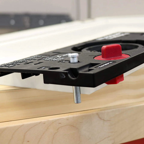 Close-up of concealed cabinet hinge jig with 35mm Forstner bit and metal bushing drill guide for precise hinge cup holes.