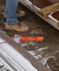 Heavy Duty Outdoor Extension Cord Safety Cover and Weatherproof Connector Protector in mud and snow, bright orange, 10-16 gauge cords