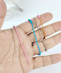 Hand holding assorted colored metal ball bead chains for DIY crafts, similar to 50 Pcs 4 Inch Ball Beads Chain With Connectors.