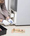 Technician installing Drop Down Chest Freezer Hinge Replacement with durable metal spring, shown with a toolbox next to a refrigerator.